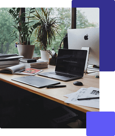 一張現代化的辦公桌,桌上有筆記型電腦、平板電腦、文件和辦公室用品,靠近窗戶,背景是植物和 iMac,非常適合探索香港的 AI 創新。. 香港AI